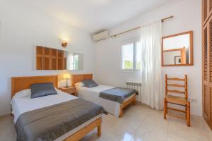 Un dormitorio con 2 camas y una silla. en Villa Can Prats, en Santa Eulària des Riu