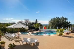 a patio with chairs and an umbrella and a pool at Villa Can Prats in Santa Eularia des Riu