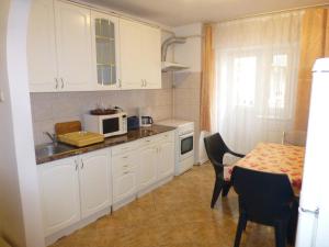 una cucina con mobili bianchi e un tavolo con un forno a microonde di Apartament Zippi Republicii RHBM a Baia Mare
