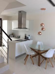 a kitchen with a glass table and white chairs at Villa Bianco in Orihuela Costa