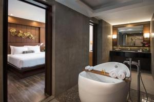 a bathroom with a tub and a bedroom with a bed at Casa Nithra - SHA Extra Plus in Bangkok
