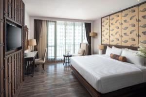 a hotel room with a bed and a desk and a television at Casa Nithra - SHA Extra Plus in Bangkok