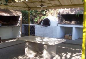 a picnic table under a tent with a pizza oven at Aparts Piscu Yaco Almendros in Merlo