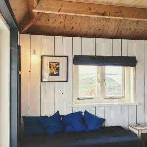 a bedroom with a bed with blue pillows and a window at Groeten uit Hoogmade - rural cottage in Hoogmaden