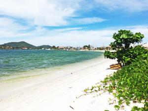 a beach with a white sand and blue water at Apartamento Cabo Frio 3Q in Cabo Frio
