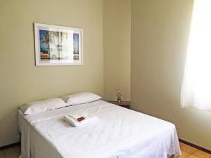 Un dormitorio con una cama blanca con una toalla. en Apartamento Cabo Frio 3Q, en Cabo Frío