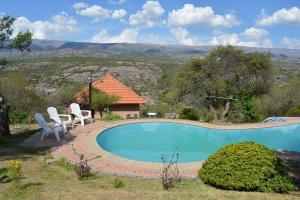 a swimming pool with two chairs and a house at Cabañas Del Rio in Mina Clavero +29 photos