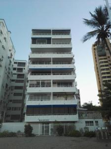 ein hohes weißes Gebäude mit einer Palme davor in der Unterkunft Apartamento Vista Al Mar El Rodadero in Santa Marta