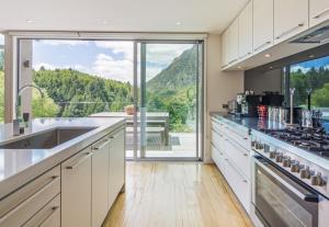 a kitchen with white cabinets and a large window at Riverview Retreat Holiday Home by MajorDomo in Queenstown