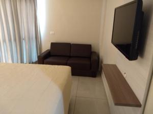 uma sala de estar com um sofá e uma televisão de ecrã plano em AP 306 Flat Beira mar praia de Tambaú em João Pessoa