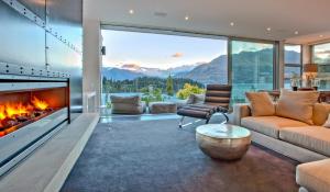 a living room with a fireplace and a view of mountains at Kakara Moana in Queenstown