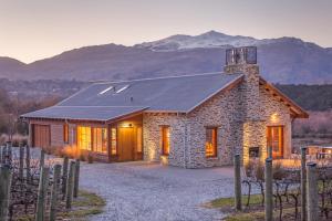 a stone house with mountains in the background at Shotover Point Luxury Holiday Home by MajorDomo in Queenstown