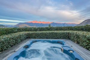 una bañera de hidromasaje en un campo con montañas al fondo en Bellbrae Luxury Villa by MajorDomo, en Queenstown