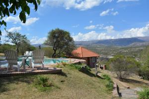 a table and two chairs next to a swimming pool at Cabañas Del Rio in Mina Clavero
