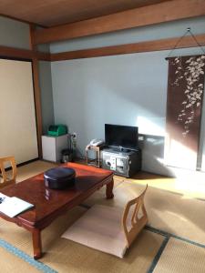 a living room with a table and a television at Shiunso in Nikko