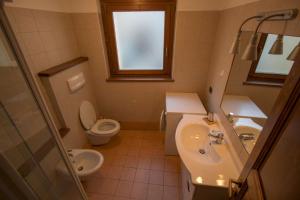bagno con lavandino, servizi igienici e finestra di Casa Alfredo a Cogne
