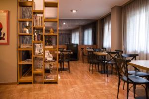 Habitación con mesas, sillas y estante para libros. en Hotel Maroussi, en Atenas