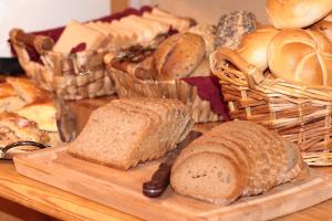 a table with bread on a cutting board and baskets of bread at Hotel Pension Eichenhof in Fügenberg