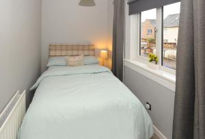 a small bedroom with a bed and a window at Spacious 3 bedroom house in Stirling