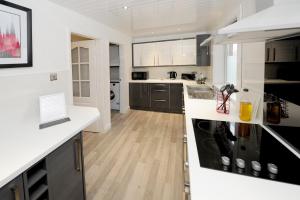 a kitchen with black and white appliances and wooden floors at Spacious 3 bedroom house in Stirling