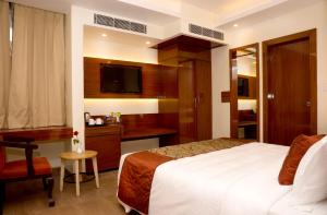 a hotel room with a bed and a desk at Amalfi Grand in Patna