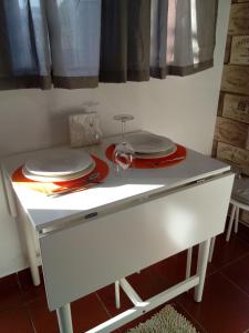 una mesa blanca con platos y copas de vino. en Casa da Vovó (Casa do Tapado) en Amarante
