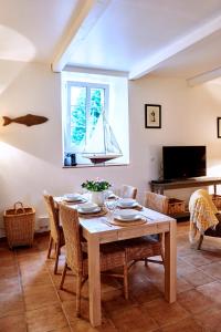 una sala da pranzo con tavolo e una barca a vela in una finestra di Manoir des petites bretonnes a Saint-Quay-Perros