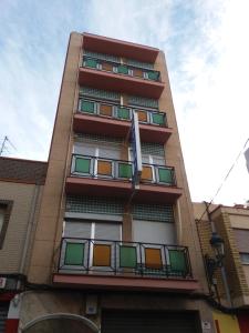 a tall building with colorful windows and a flag at Hostal La Pilarica in Paterna