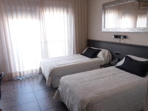 a hotel room with two beds and a window at Hostal La Pilarica in Paterna