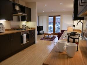 een keuken en een woonkamer met zwarte kasten en houten vloeren bij 8 Swan House in Carnforth
