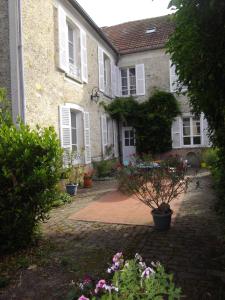 a house with a courtyard with potted plants and flowers at La Fruitiere in Saints