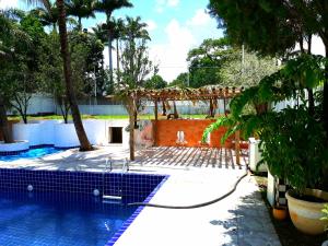 a swimming pool with a fence and trees in a yard at Roteiro de charme in Paranoá