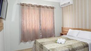 a bedroom with a bed with two white shoes on it at Coral Palace Hotel in Sangão +25 photos