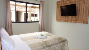 a bedroom with a bed and a flat screen tv at Coral Palace Hotel in Sangão