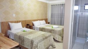 a hotel room with two beds and a shower at Coral Palace Hotel in Sangão