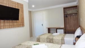 a hotel room with two beds and a flat screen tv at Coral Palace Hotel in Sangão