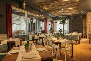 een restaurant met houten tafels, stoelen en ramen bij Hotel ABC in Leskovac