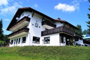 a white building with wooden balconies on top of a hill at Penzion Sumavacek in Bayerisch Eisenstein