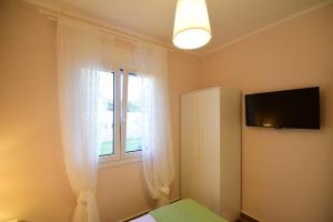 a bedroom with a window and a flat screen tv at Stavros Beach Garden Villa in Stavros