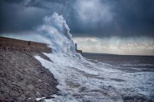 a wave crashing against a wall in the ocean at Apartment Mary street in Porthcawl