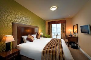 a hotel room with a large bed and a desk at George Limerick Hotel in Limerick