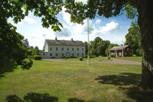 ein großes weißes Haus mit einem Baum im Vordergrund in der Unterkunft B&B Kvarntorps Herrgård in Forshaga