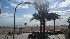a view of a beach with palm trees and a street light at Apartamento a 10 metros del mar in Cullera