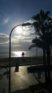 a street light with a palm tree on the beach at Apartamento a 10 metros del mar in Cullera
