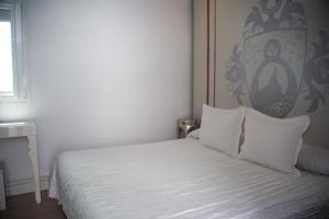 1 cama con sábanas blancas y almohadas en una habitación en La Princesa y El Guisante, en Conil de la Frontera