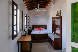 a bedroom with a bed and a desk and windows at Southern Comforts - Galle Fort in Galle