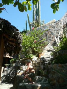 a young boy sitting on some rocks with a camera at La Loma Linda: Bungalows, Yoga and Feldenkrais in Zipolite
