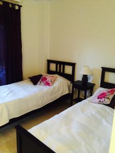 a bedroom with two beds and a table with a lamp at Jardines de Nueva Galera en Estepona in Estepona