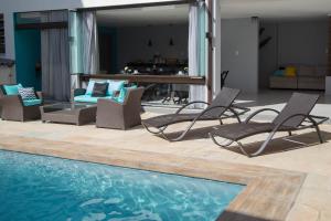 um grupo de cadeiras sentadas ao lado de uma piscina em REF House Barra Da Tijuca no Rio de Janeiro