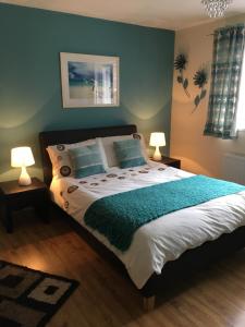1 dormitorio con 1 cama con paredes azules y 2 lámparas en Maple Tree Guesthouse, en Gretna Green